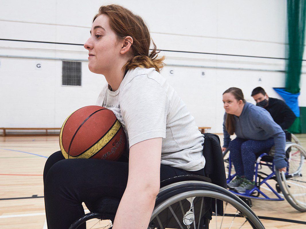 Three people playing wheelchair basketball