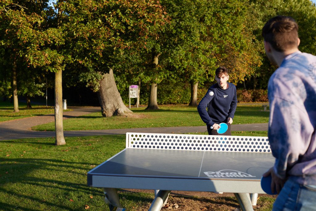 2 young men playing table tennis outdoors