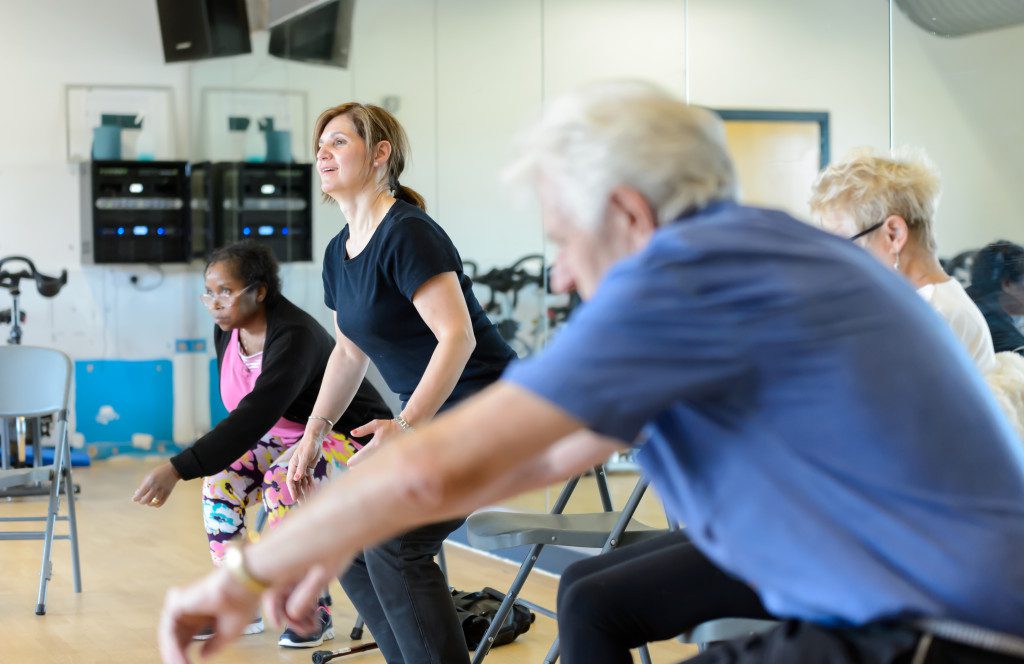people doing a sit to stand exercise in a group class
